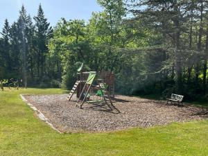 Un patio de juegos en un parque con un conjunto de juegos y un banco. en Gite de la Renardière, en Paunat