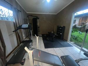 una habitación con un gimnasio con máquinas de correr y una ventana en Hooggelegen Estate, en White River