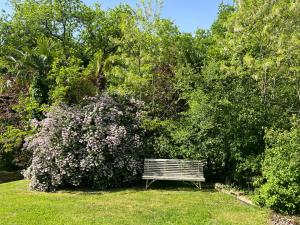 Un banco del parque sentado en el césped junto a un arbusto. en Gite de la Renardière, en Paunat