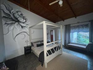 Un dormitorio con una cama con una flor pintada en la pared. en Hooggelegen Estate, en White River
