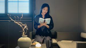 a woman is reading a book in a room at 대전 유성 낙원온천호텔 by 아늑 in Yusŏng