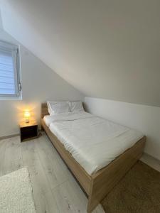 a bedroom with a bed with a lamp on a table at Appartement cosy 2 chambres in Jougne