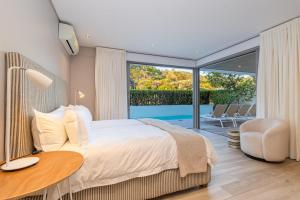 a bedroom with a bed and a table and a balcony at Ocean View Villa - Keurboomstrand in Plettenberg Bay +57 photos