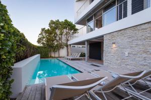 a swimming pool with chairs and a house at Ocean View Villa - Keurboomstrand in Plettenberg Bay