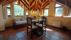 a dining room with a table and chairs and a couch at Taiquen Apart Hotel in San Martín de los Andes
