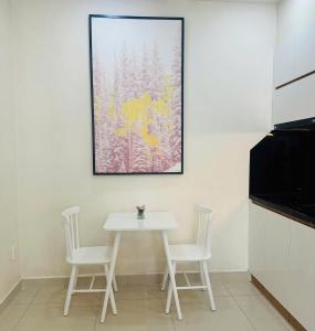 a white table and chairs in a kitchen with a painting at The Lume Studio - Tresor D4 in Ho Chi Minh City
