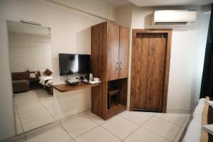 Hotel Kartiki في أورانغاباد: غرفة بها تلفزيون وخزانة خشبية