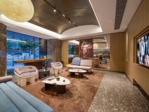 a living room with a blue couch and tables at Arthur Hotel Baiyun Station Xinshixu Subway Station Guangzhou in Guangzhou