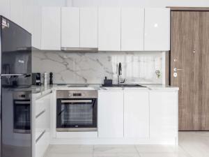 uma cozinha com armários brancos, um lavatório e um forno em Arcade Apartments 1st floor em Volos