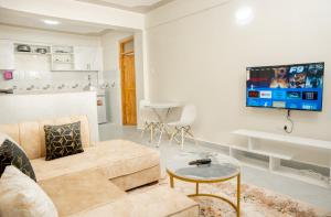 un soggiorno con un divano e una TV a parete di Amno Elite Suites a Naivasha