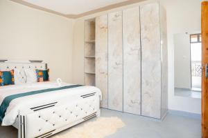 una camera con un letto bianco e un grande armadio di Amno Elite Suites a Naivasha