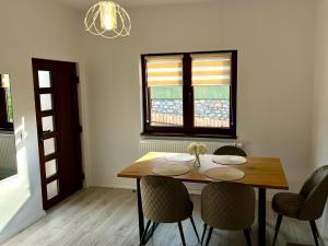 a dining room with a wooden table and chairs at Bálint Apartman 1 in Valea Strîmbă