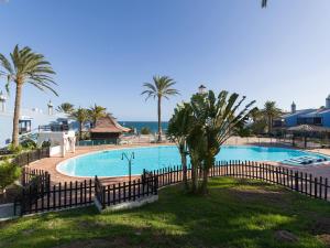 a large swimming pool with palm trees and a fence at Blue Horizon Retreat in Playa del Aguila