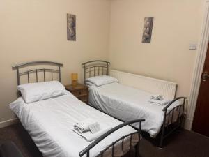 twee bedden in een kamer met witte lakens bij Woodfield Lodge Apartments in Blackpool