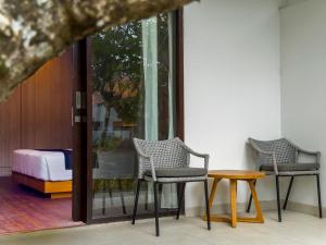 ein Zimmer mit zwei Stühlen und einem Tisch und einem Bett in der Unterkunft eL Hotel & Resort Bali Sanur in Sanur + 23 Fotos