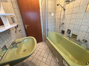 ein Badezimmer mit einer grünen Badewanne und einem Waschbecken in der Unterkunft Haus Aktiv Top2 in Winterberg + 25 Fotos