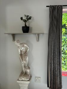 a statue sitting on a shelf next to a window at Innessfree Cottage in Doordrift