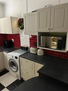 a kitchen with white cabinets and a washing machine at Innessfree Cottage in Doordrift