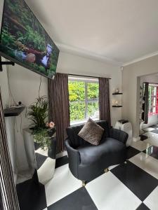a living room with a black chair and a checkered floor at Innessfree Cottage in Doordrift +4 photos