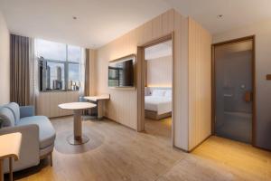 a hotel room with a bed and a living room at Hanting Hotel Chongqing Lianglukou Caiyuanba in Chongqing