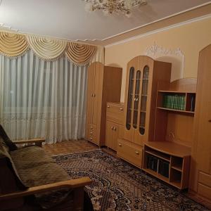 a living room with a chair and a cabinet at Квартира in Sumy