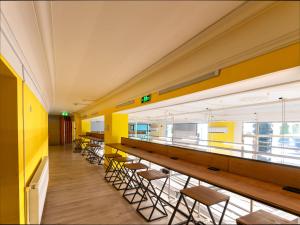 una fila de mesas y sillas en una habitación con paredes amarillas en Capsule Hotel Happy lounge, en Tiflis