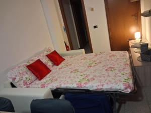 a bed with red pillows on it in a room at Bilocale comodamente collegato con centro Milano in Garbagnate Milanese