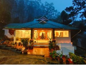 une petite maison avec un toit bleu et des plantes en pot dans l'établissement Great Escapes Resorts, à Chinnakanal