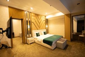 una habitación de hotel con una cama y un televisor en Green Park Hotel, en Shymkent
