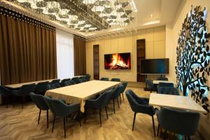 Una sala de conferencias con mesas y sillas y una chimenea. en Green Park Hotel, en Shymkent