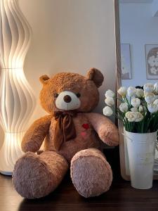 a teddy bear sitting on a table next to a vase of flowers at Gia An Homestay in Phú Thú +1 photo