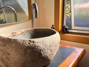 een stenen wastafel in een badkamer met een raam bij Pandora Cottage Beachfront in Raglan