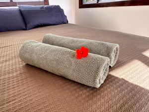 een bed met een bank waarop een rode bloem staat bij Pandora Cottage Beachfront in Raglan