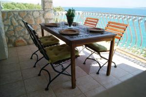 a wooden table with four chairs on a balcony at Apartmani Braco Caratan in Zavala