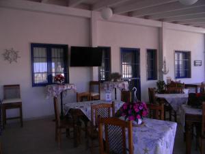 a dining room with tables and chairs and a flat screen tv at B&B Giorgio La Pira in Santa Maria del Focallo