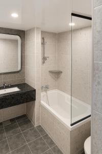 Magnum Nampo Hotel في Jung-gu: حمام مع حوض استحمام ومغسلة