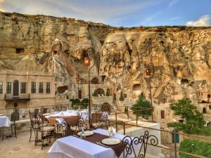 a restaurant with tables and chairs in front of a cliff at Yunak Evleri Cappadocia in Urgup