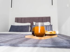 um copo de suco de laranja e um prato de comida na cama em Arcade Apartments 1st floor em Volos