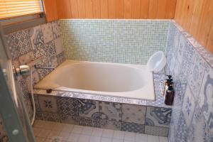 松山一棟貸し宿Tsuji في ماتسوياما: حوض استحمام في حمام به بلاط ازرق +22 صورة