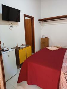 ein Schlafzimmer mit einem roten Bett und einem Fernseher an der Wand in der Unterkunft Cafofo de Dri in Ilha de Boipeba