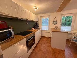 a kitchen with white cabinets and a stove top oven at Inselglück unter Reet 100m zum Strand - Garten & Privatterrasse - Hund willkommen in Karlshagen