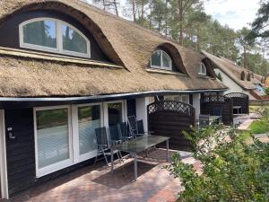 a house with a thatched roof with a table and chairs at Inselglück unter Reet 100m zum Strand - Garten & Privatterrasse - Hund willkommen in Karlshagen