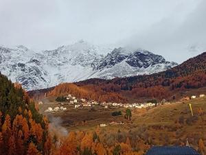 a town in a valley with a snow covered mountain at Un balcone sulla Val di Pejo in Peio