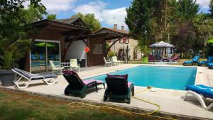 a swimming pool with chairs and a house at Les Gites de Castera in Aire-sur-lʼAdour
