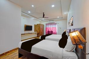 a bedroom with two beds and a flat screen tv at Super Townhouse Vanagaram Apollo Hospital Chennai Formerly V Hotels & Restaurant in Chennai
