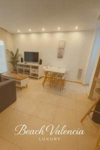 a living room with a table and a tv at BEACH VALENCIA LUXURY A40-13 Apartment with terrace and sea views in Valencia