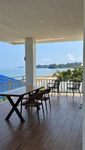 Una mesa y sillas en un balcón con vista al mar. en Buddy's Beach House Sipalay, en Lagob
