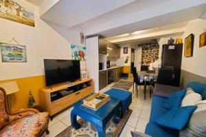 ein Wohnzimmer mit einer blauen Couch und einem Fernseher in der Unterkunft L'Occitane Maison de village climatisée in Lapalme