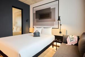 een hotelkamer met een wit bed en een stoel bij ibis Madrid Norte Las Tablas in Madrid