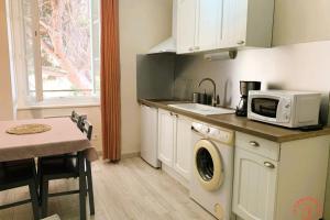 a kitchen with a washing machine and a microwave at Gîte Studio Les Cigales piscine & WIFI in Narbonne